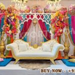 Luxury Mehndi decor setup, Sangeet function stage decoration, Indian wedding backdrop, royal wedding stage decor, colorful mehndi stage, traditional Indian wedding decor, Rajasthani umbrella wedding decor, mehndi ceremony setup, sangeet night decoration, Indian wedding sofa stage, destination wedding decor India, wedding stage setup exporter, mandap exporters India, wedding decor for USA UK Australia, luxury wedding backdrop, mehndi stage decoration supplier, Indian wedding event decor, handcrafted wedding stage, reusable wedding decor setup, DST Home Furniture wedding decor