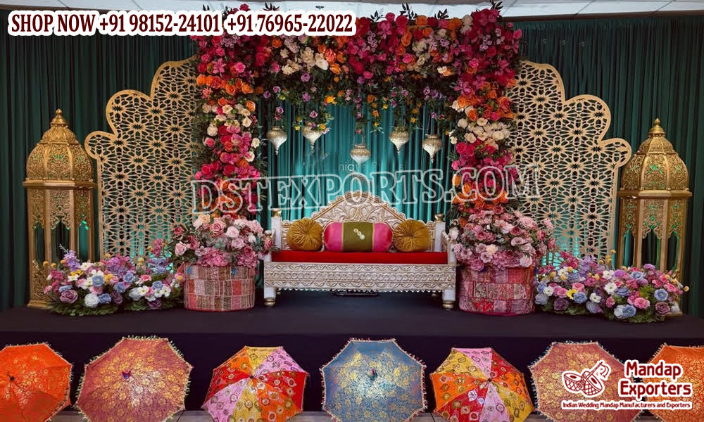 Luxury Moroccan Mehndi stage decor featuring intricate laser cut backdrop panels, colorful floral arrangements, traditional lanterns, and royal wedding sofa