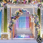 Colorful Mehndi wedding stage backdrop with carved Mughal style mirror frames, pastel drapes, floral decoration, and decorative bridal swing for Indian wedding events.