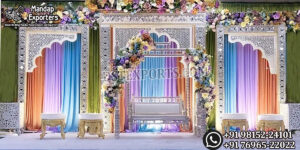 Colorful Mehndi wedding stage backdrop with carved Mughal style mirror frames, pastel drapes, floral decoration, and decorative bridal swing for Indian wedding events.
