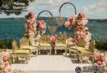 Royal German Silver Style Mandap Chair Set USA Royal German silver style mandap chair set with intricately carved metallic chairs, pastel floral backdrop, and elegant hanging chandeliers by a scenic waterfront wedding venue in the USA.