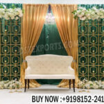 candle lit wedding stage, green gold wedding backdrop, candle wall wedding decor, luxury wedding stage backdrop, engagement stage green gold theme, wedding stage with candles, elegant wedding backdrop panels, floral frame wedding stage, modern wedding stage decor, reception stage backdrop design, candle light wedding decoration, designer wedding stage India, banquet hall wedding decor, wedding decor exporters India, premium event backdrop panels, wedding stage with green panels, contemporary wedding backdrop design