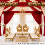 wedding mandap, luxury wedding mandap, low seating vedi chairs, Hindu wedding mandap, royal wedding setup, floral wedding mandap, red and ivory mandap décor, traditional wedding canopy, luxury wedding stage, carved wedding chairs, Indian wedding mandap décor, premium wedding vedi setup, decorative wedding drapes, wedding ceremony seating, designer mandap setup, banquet wedding mandap, elegant wedding décor, wedding stage furniture,
