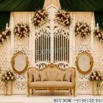 Wedding reception stage backdrop, luxury wedding gate frame, carved wedding backdrop panel, royal reception stage décor, floral wedding stage setup, wedding gate backdrop design, premium wedding stage manufacturer, Indian wedding backdrop supplier, engagement stage decoration, nikah stage backdrop, designer wedding frame, luxury wedding sofa stage, carved white wedding panels, indoor wedding reception décor, banquet hall wedding backdrop, floral stage decoration, wedding event décor supplier, royal wedding stage setup, destination wedding reception backdrop