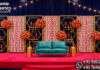 Modern Box Style Candle Wall Stands For Wedding Stage candle lit wedding stage, green gold wedding backdrop, candle wall wedding decor, luxury wedding stage backdrop, engagement stage green gold theme, wedding stage with candles, elegant wedding backdrop panels, floral frame wedding stage, modern wedding stage decor, reception stage backdrop design, candle light wedding decoration, designer wedding stage India, banquet hall wedding decor, wedding decor exporters India, premium event backdrop panels, wedding stage with green panels, contemporary wedding backdrop design