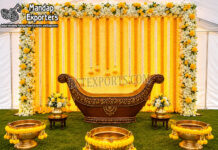 Outdoor Indian Wedding Pithi Ceremony Decor Setup Luxury outdoor Indian wedding pithi ceremony setup featuring a yellow floral backdrop, traditional decorative seating, brass urli bowls, flower arrangements, and festive haldi ceremony décor.