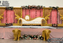 Traditional Theme Thread Ceremony Stage Decor Elegant Indian wedding stage setup featuring a royal white and gold bridal sofa, ornate elephant carved panels, pink drapes, floral arrangements, and decorative elephant statues for traditional ceremonies.