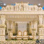 South Indian temple mandap, luxury wedding mandap decor, temple style wedding stage, traditional wedding mandap, grand wedding backdrop, white and gold mandap, carved wedding stage, premium wedding decor, Indian wedding stage setup, royal wedding mandap, handcrafted mandap design, South Indian wedding decor, designer wedding stage, ornate temple backdrop, luxury wedding furniture, wedding event decor manufacturer, carved pillar mandap, wedding reception stage, Hindu wedding mandap setup