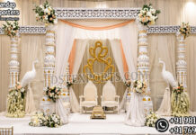 Prestige Look Indian Wedding Mandap Luxury White and Gold Indian Wedding Mandap with six carved pillars, elegant drapes, floral arrangements, decorative peacock stands, royal wedding chairs, and traditional Hindu wedding stage setup by DST Exports.