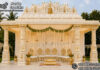 White Gold Carved Temple Style Wedding Mandap White gold carved temple-style wedding mandap with ornate pillars, a grand Ganesha crown and traditional Hindu wedding stage seating.